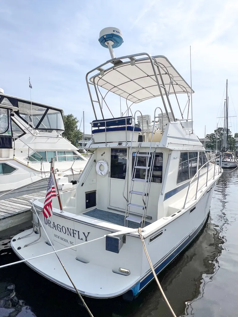 The Image of 1987 Tollycraft 34 Sport Sedan docked, featuring a spacious deck and flybridge. - 0