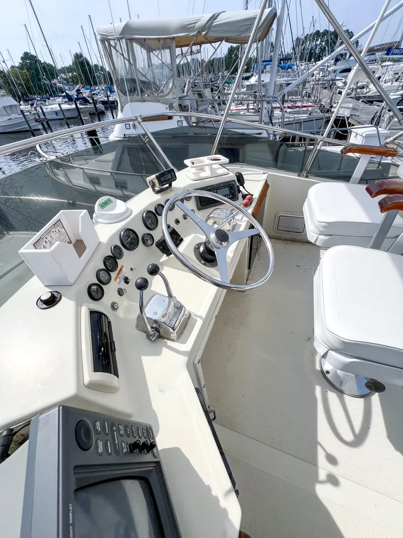 Slide: The Image of 1987 Tollycraft 34 Sport Sedan helm with steering wheel and controls, docked at marina. - 13
