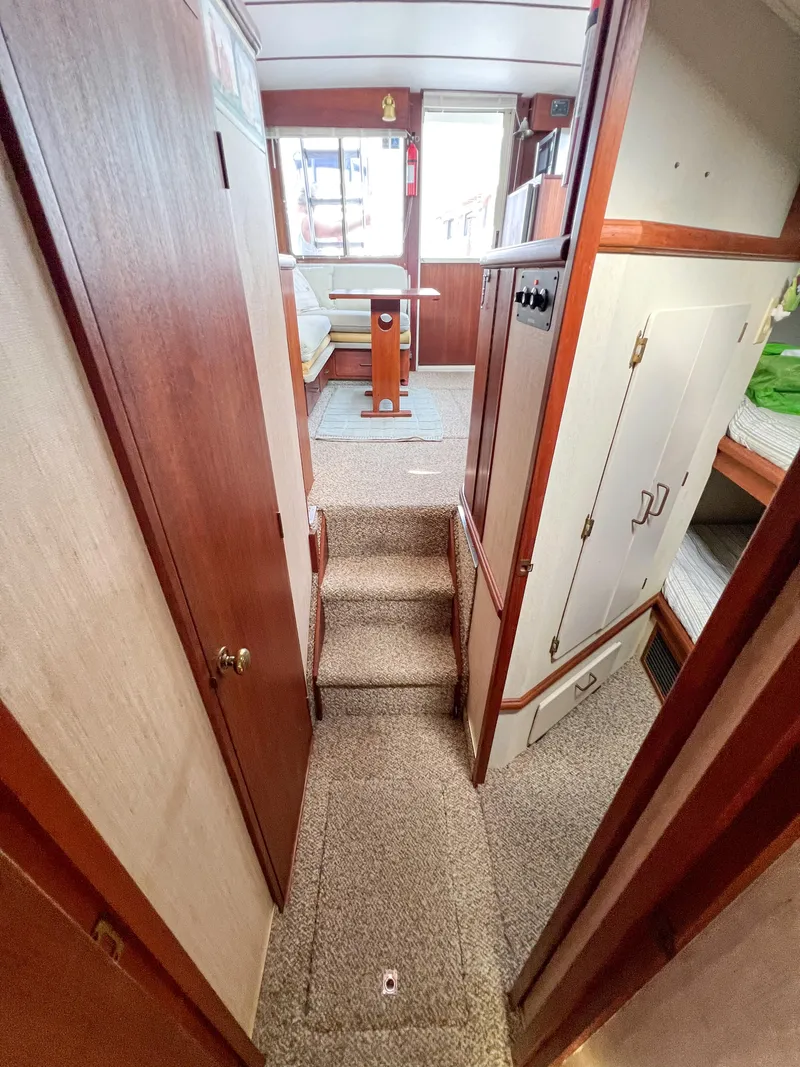 Slide: The Image of 1987 Tollycraft 34 Sport Sedan interior hallway with carpeted steps and wooden cabinetry. - 35