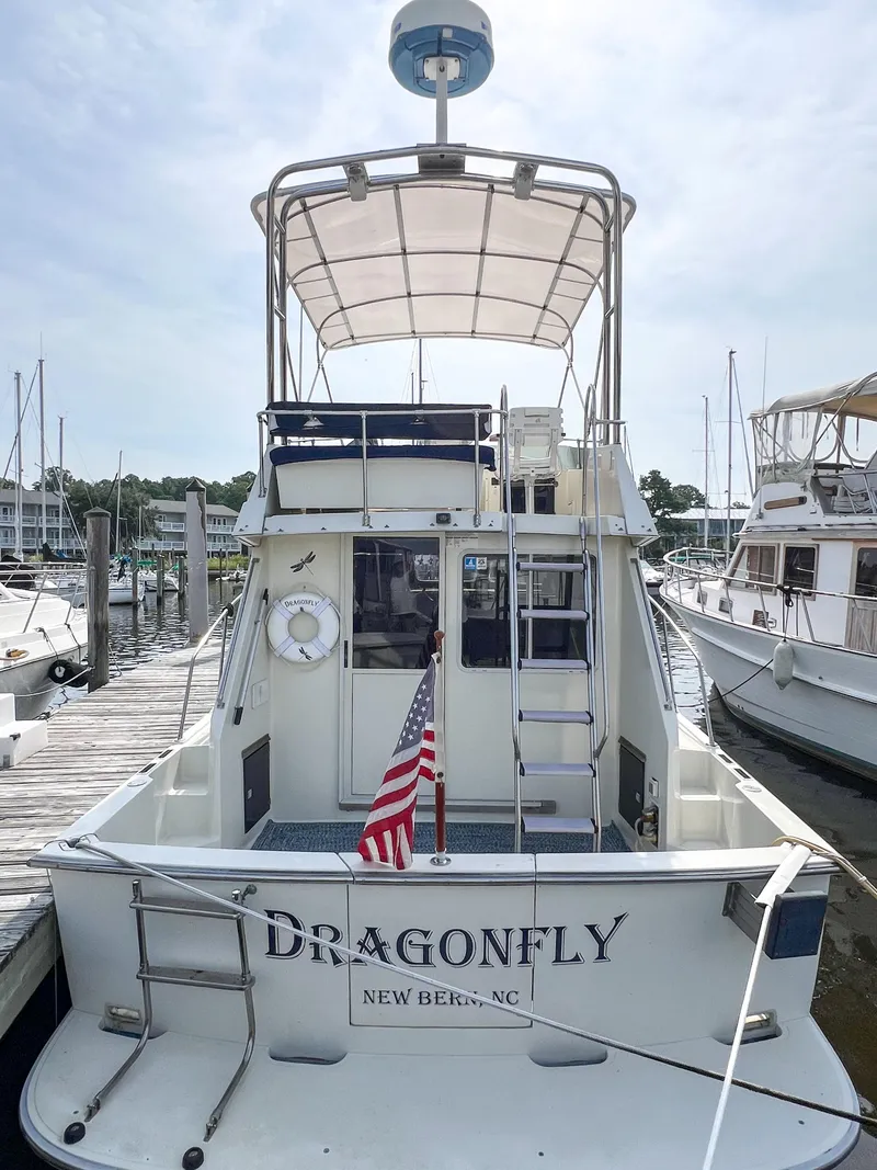 Slide: The Image of 1987 Tollycraft 34 Sport Sedan boat docked, featuring "Dragonfly" name and American flag. - 5