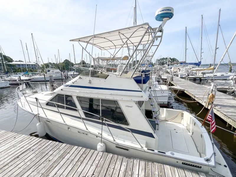 Slide: The Image of 1987 Tollycraft 34 Sport Sedan docked at a marina, featuring a spacious deck and flybridge. - 7