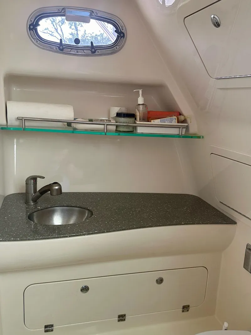 Slide: The Image of 2016 Boston Whaler 315 Conquest bathroom with sink, countertop, and storage shelf. - 26