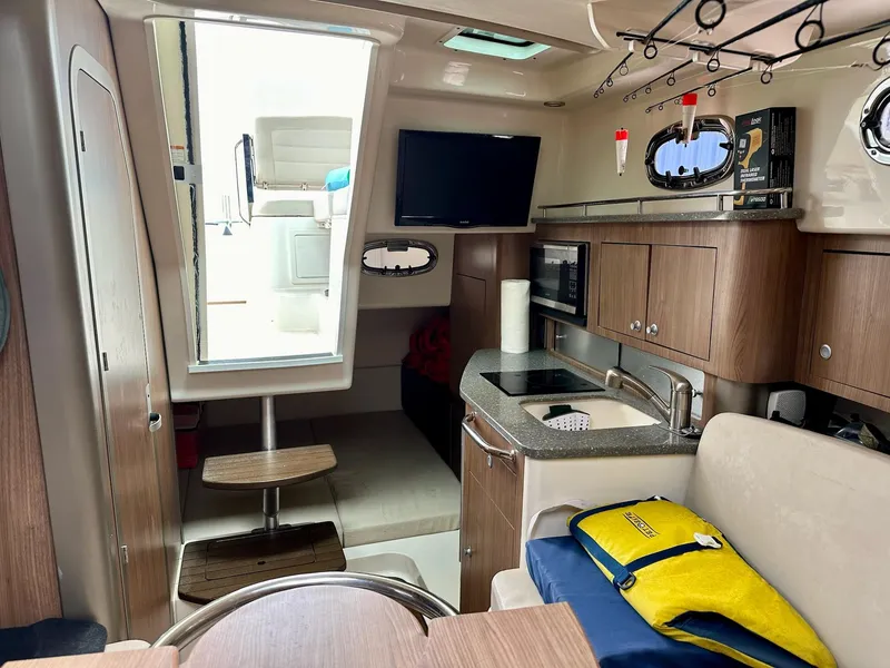 Slide: The Image of Interior of 2016 Boston Whaler 315 Conquest, featuring kitchen, seating, and fishing rod storage. - 29