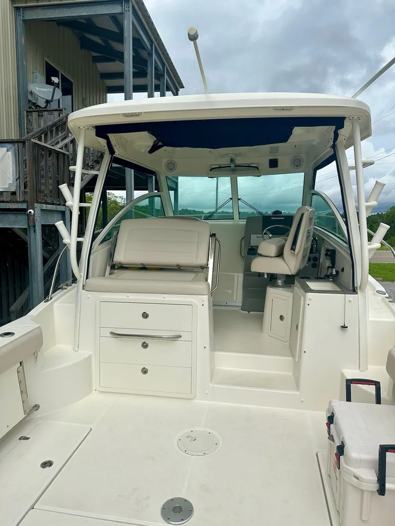 Slide: The Image of 2016 Boston Whaler 315 Conquest boat interior with seating and helm, under cloudy sky. - 6