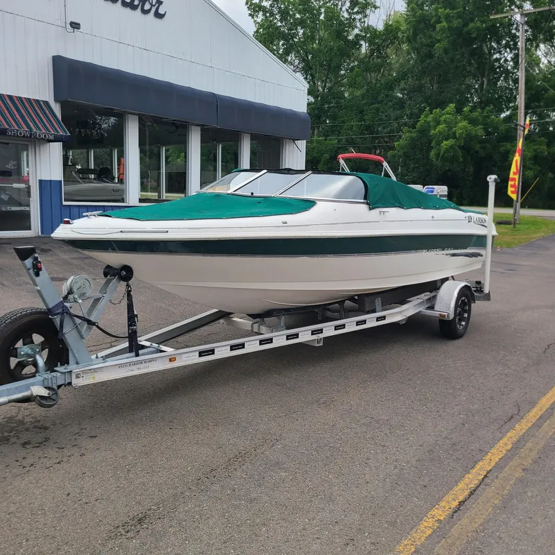 The Image of 1999 Larson 206 boat on trailer outside dealership. - 0