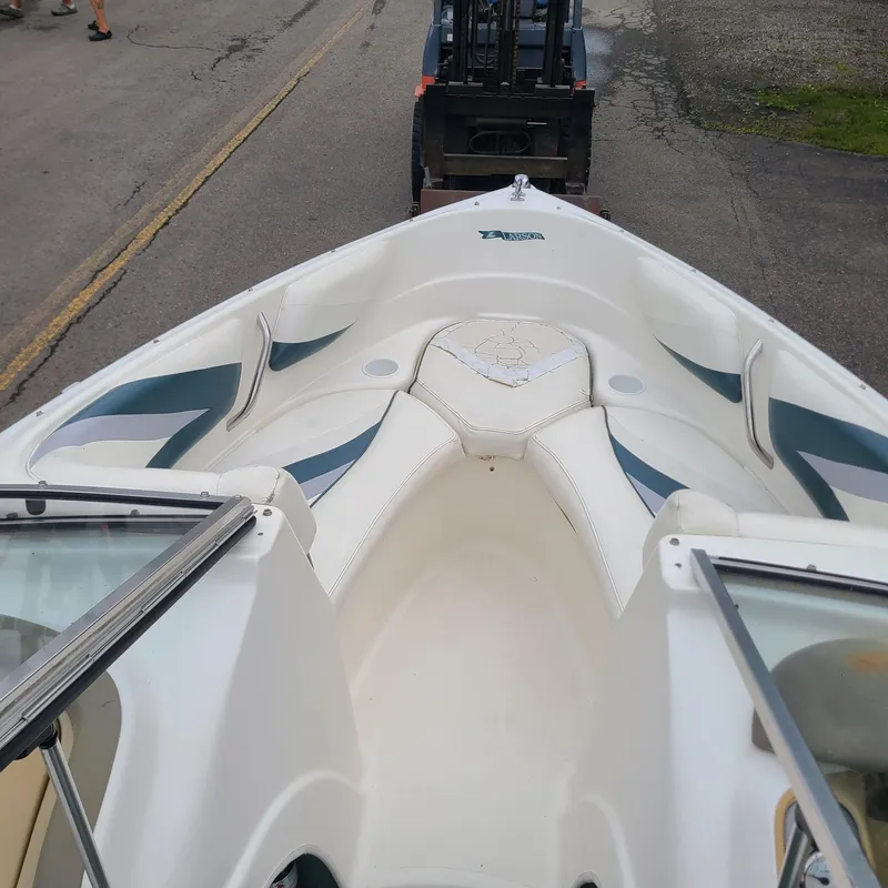 Slide: The Image of 1999 Larson 206 boat interior with white seating, parked on a road. - 11