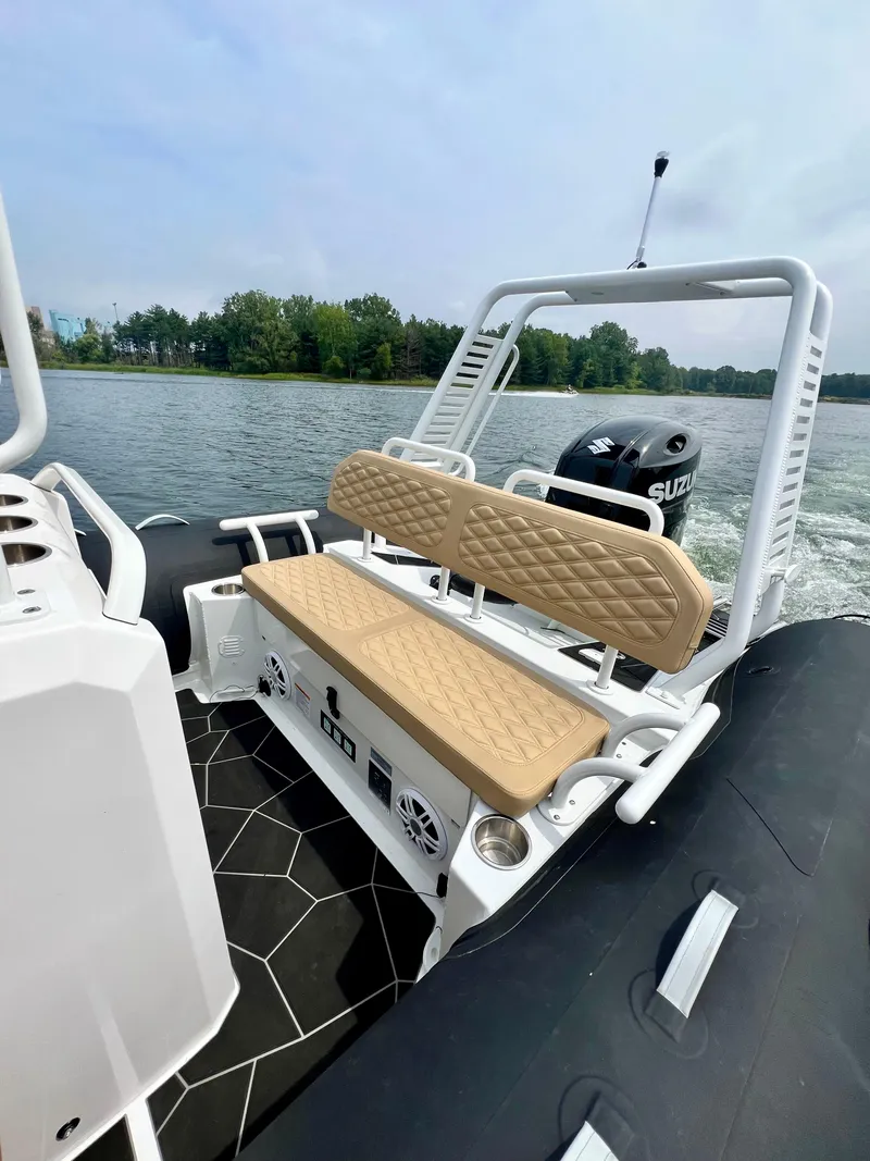 Slide: The Image of 2024 Highfield SP 600 RIB with tan seating and Suzuki outboard motor on a lake. - 16