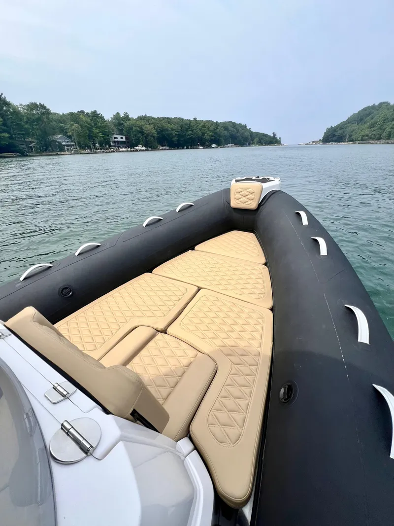 Slide: The Image of 2024 Highfield SP 600 RIB with beige seating, cruising on a scenic waterway. - 19