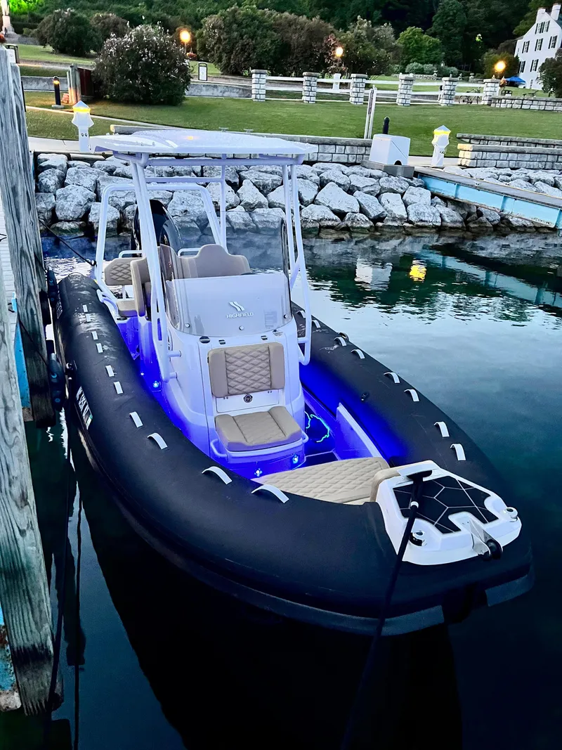 Slide: The Image of 2024 Highfield SP 600 RIB boat docked with blue LED lights at dusk. - 2