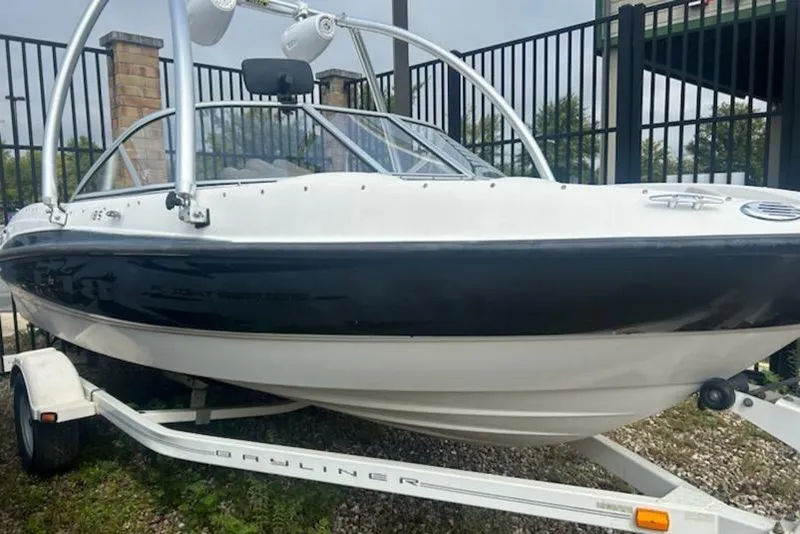 Slide: The Image of 2010 Bayliner 185 Flight boat on trailer, black and white exterior, parked outdoors. - 1