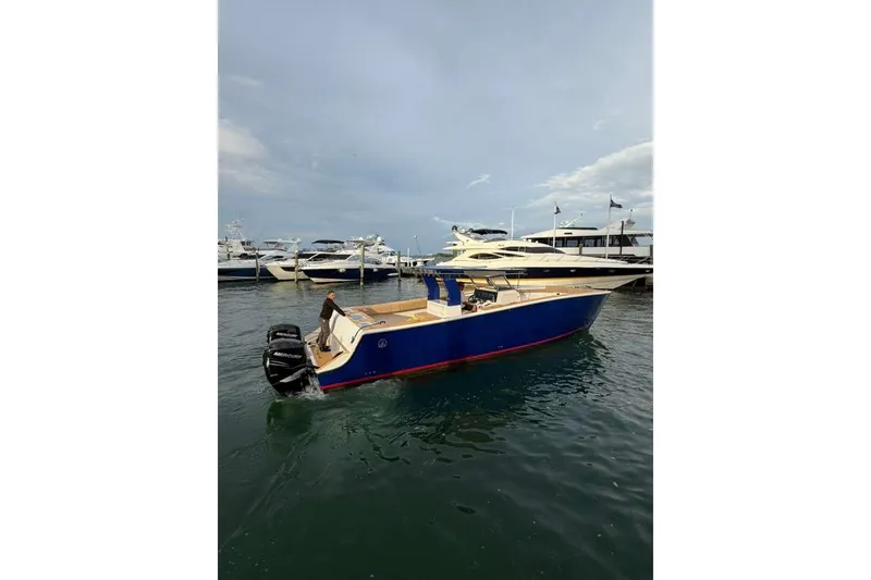 Slide: The Image of 2024 Custom Catamaran SET CAT in marina, featuring sleek blue design and dual Mercury engines. - 104