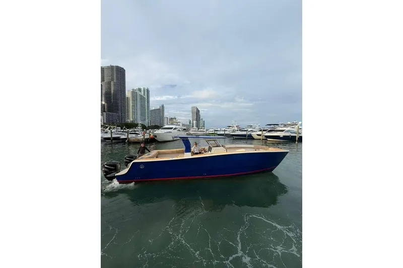 Slide: The Image of 2024 Custom Catamaran SET CAT cruising near a marina with city skyline backdrop. - 57