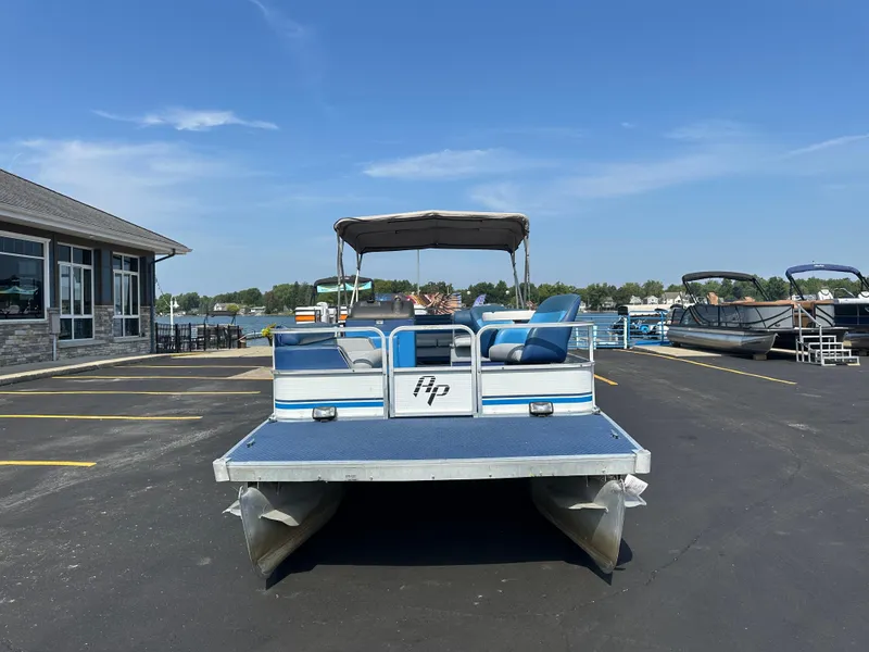 Slide: The Image of 1989 AquaPatio 24 pontoon boat parked in a marina lot under a clear blue sky. - 4