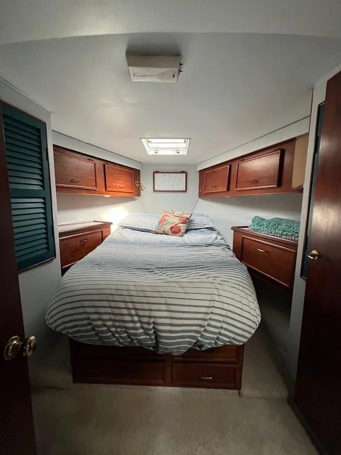 Slide: The Image of 1987 Ocean Yachts Super Sport cabin with bed, wooden cabinets, and striped bedding. - 12