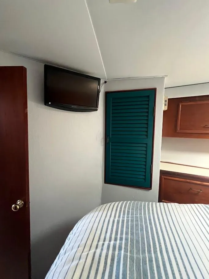 Slide: The Image of 1987 Ocean Yachts Super Sport cabin interior with bed, TV, and wooden cabinets. - 13