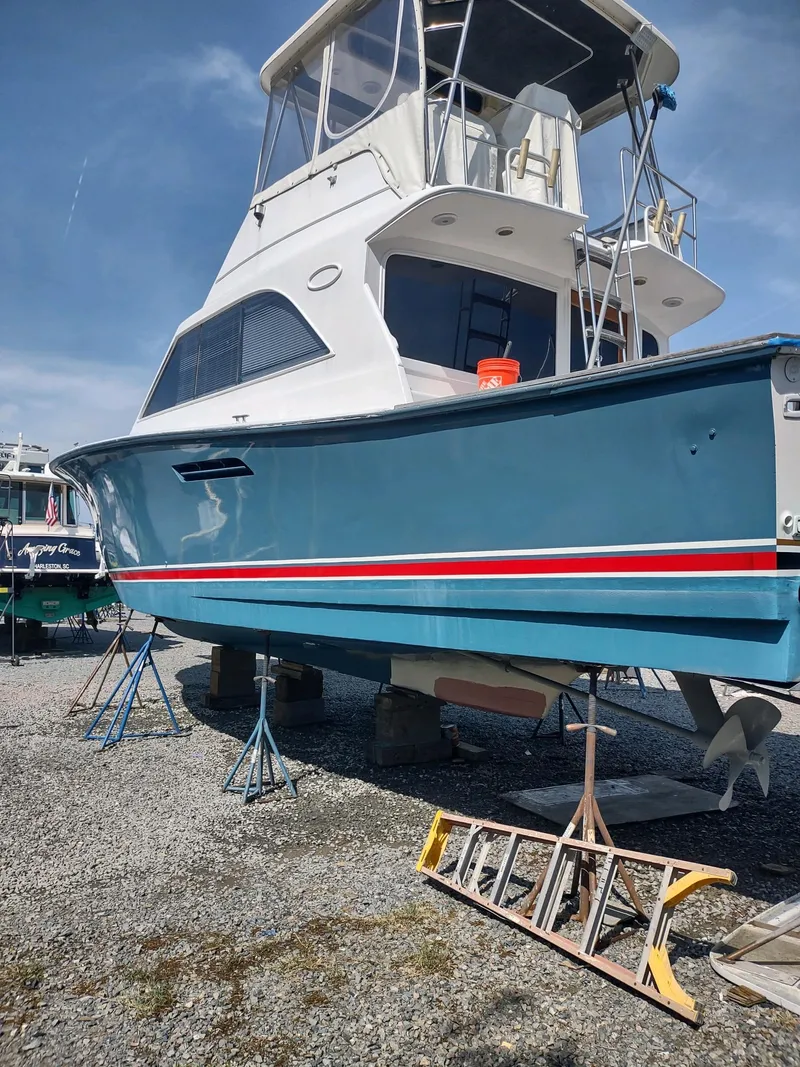 Slide: The Image of 1987 Ocean Yachts 44 Super Sport boat on dry dock, blue hull, red stripe. - 15