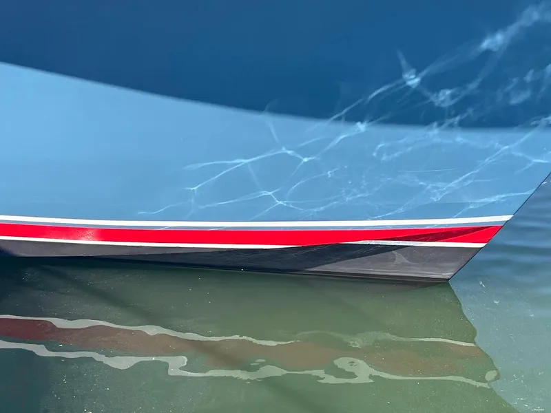 Slide: The Image of 1987 Ocean Yachts Super Sport boat hull with red stripe reflected in water. - 2