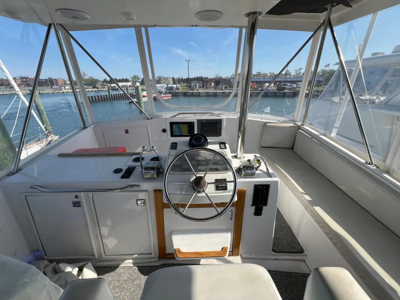 Slide: The Image of 1987 Ocean Yachts Super Sport helm with steering wheel, controls, and waterfront view. - 24