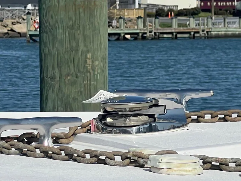 Slide: The Image of 1987 Ocean Yachts Super Sport boat cleat with chain, docked by the water. - 33