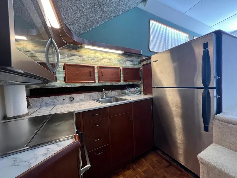 Slide: The Image of 1987 Ocean Yachts Super Sport kitchen with stainless steel appliances and wooden cabinetry. - 5