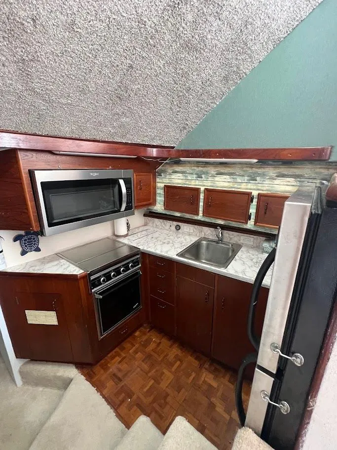 Slide: The Image of 1987 Ocean Yachts Super Sport kitchen with wood cabinets, microwave, and stainless steel sink. - 6