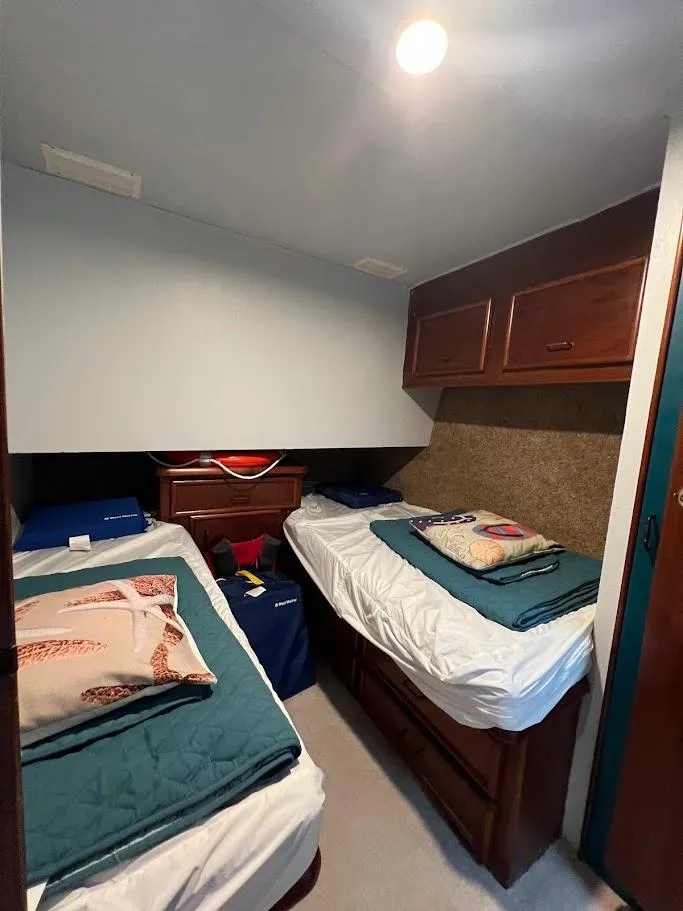 Slide: The Image of 1987 Ocean Yachts Super Sport cabin with twin beds and wooden storage cabinets. - 8