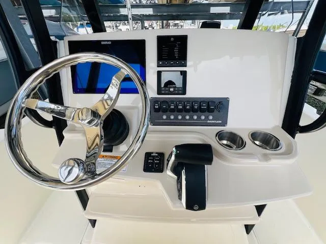 Slide: The Image of 2023 Boston Whaler 250 Dauntless helm with steering wheel, controls, and display screen. - 26
