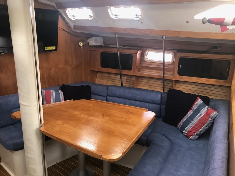 Slide: The Image of Interior of a 1997 Catalina 400 sailboat with blue seating and wooden table. - 3