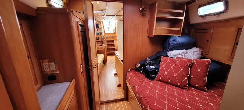 Slide: The Image of Cozy interior of 1997 Saga 43 sailboat with wooden furnishings and red-patterned bedding. - 11