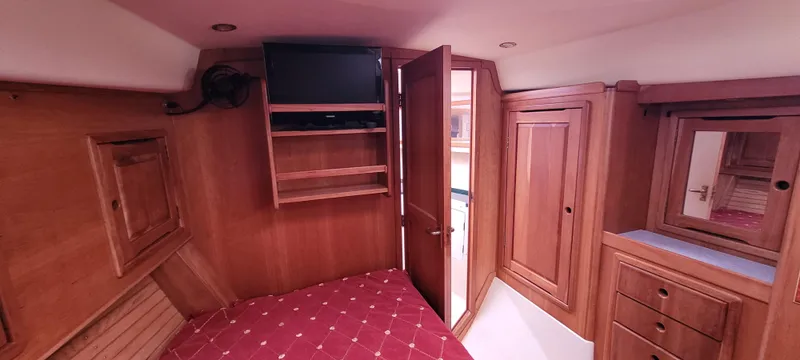 Slide: The Image of Cozy cabin interior of 1997 Saga 43 yacht with wood paneling and red bedding. - 13