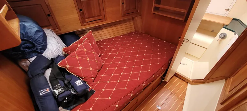 Slide: The Image of Cozy cabin interior of 1997 Saga 43 sailboat with red bedding and wooden furnishings. - 14