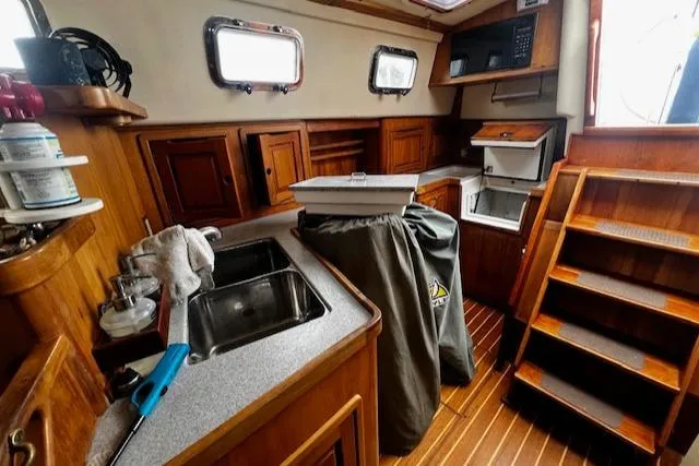 Slide: The Image of Interior of 1997 Saga 43 sailboat with wooden cabinetry and compact kitchen area. - 21
