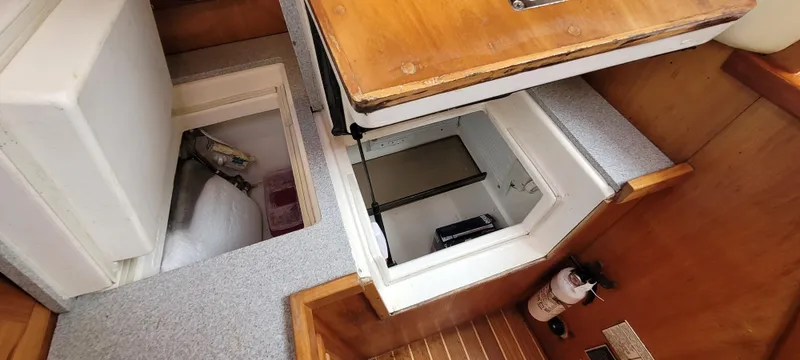 Slide: The Image of Interior view of a 1997 Saga 43 yacht, featuring open storage compartments and wooden finishes. - 28