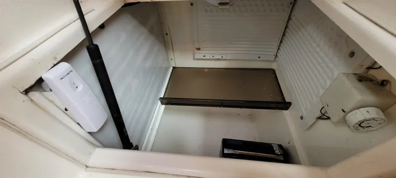 Slide: The Image of Empty refrigerator interior of a 1997 Saga 43 boat, featuring shelves and a temperature control knob. - 29