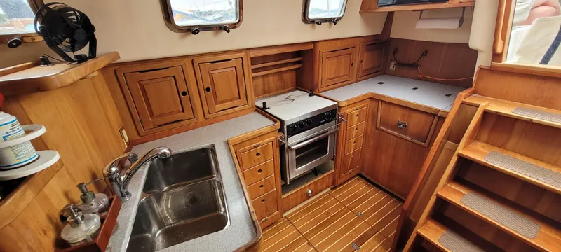 Slide: The Image of 1997 Saga 43 yacht kitchen with wooden cabinetry, stainless steel sink, and compact stove. - 7