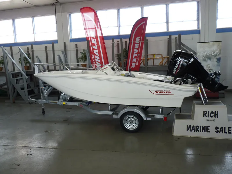 Slide: The Image of 2024 Boston Whaler 130 Super Sport boat on trailer in showroom. - 2