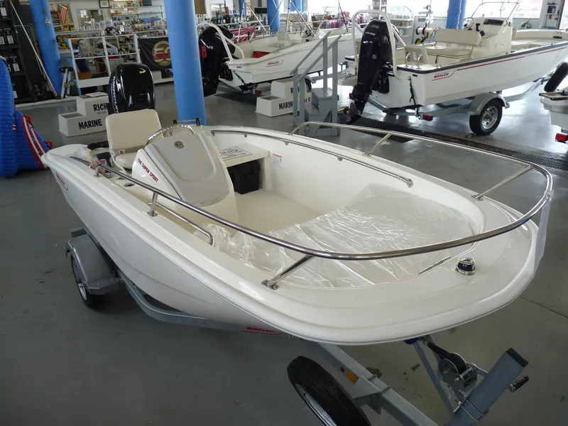 Slide: The Image of 2024 Boston Whaler 130 Super Sport boat in showroom, featuring sleek design and modern controls. - 5