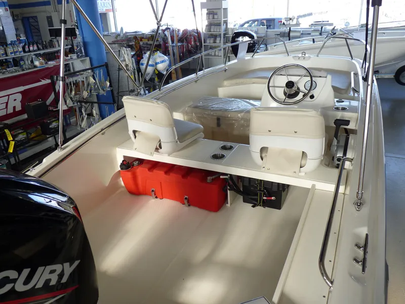 Slide: The Image of 2024 Boston Whaler 160 Super Sport interior with seating and steering wheel in showroom. - 2