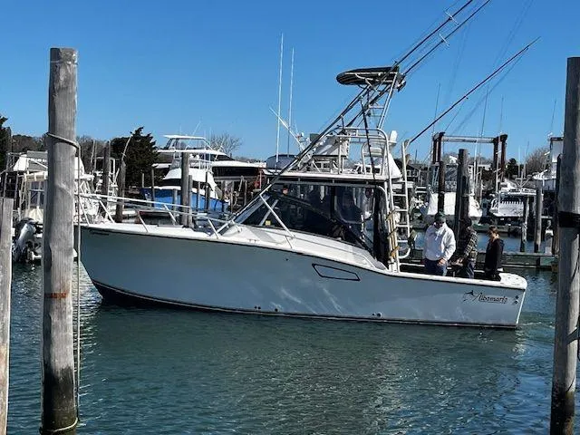 The Image of 1996 Albemarle 305 boat docked in marina, clear blue sky, two people onboard. - 0