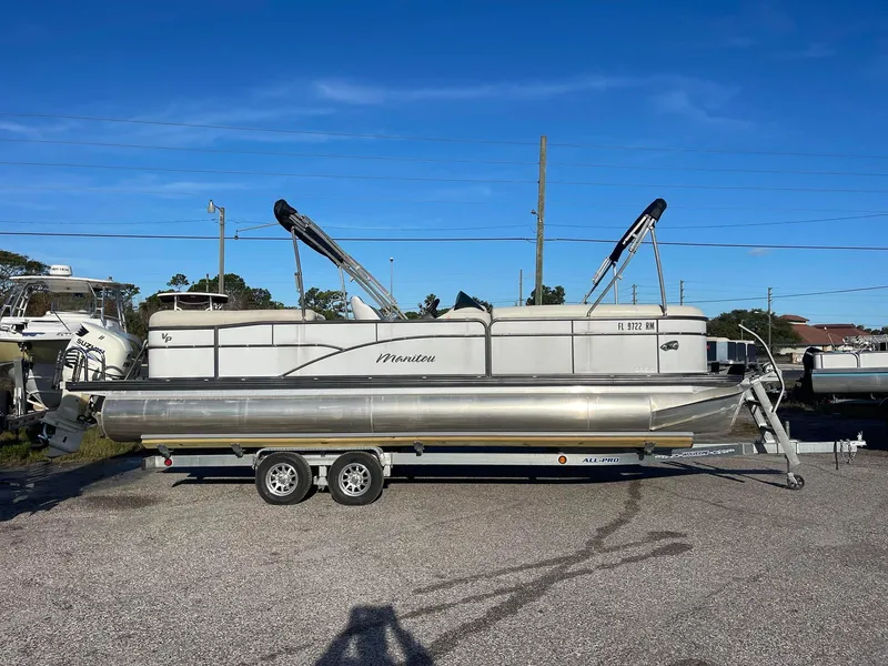 Slide: The Image of 2017 Manitou 25 Oasis pontoon boat on a trailer in a parking lot. - 0