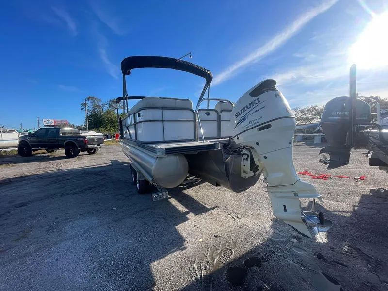 Slide: The Image of 2017 Manitou 25 Oasis pontoon boat with Suzuki outboard motor in a sunny outdoor setting. - 10