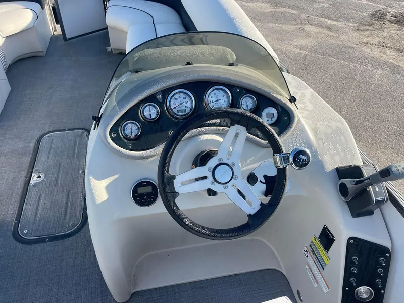 Slide: The Image of 2017 Manitou 25 Oasis boat dashboard with steering wheel and gauges. - 2