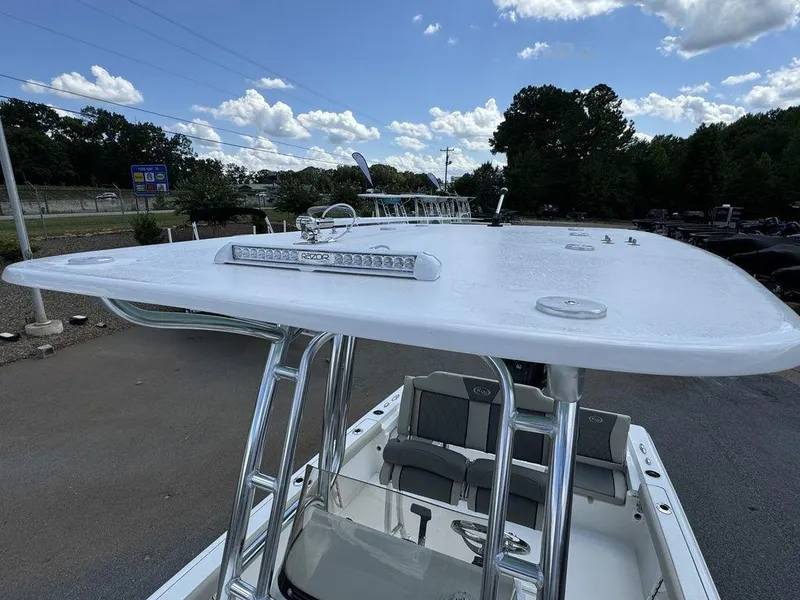 Slide: The Image of 2025 Key West 230 BR boat with T-top and seating, parked outdoors under a blue sky. - 6