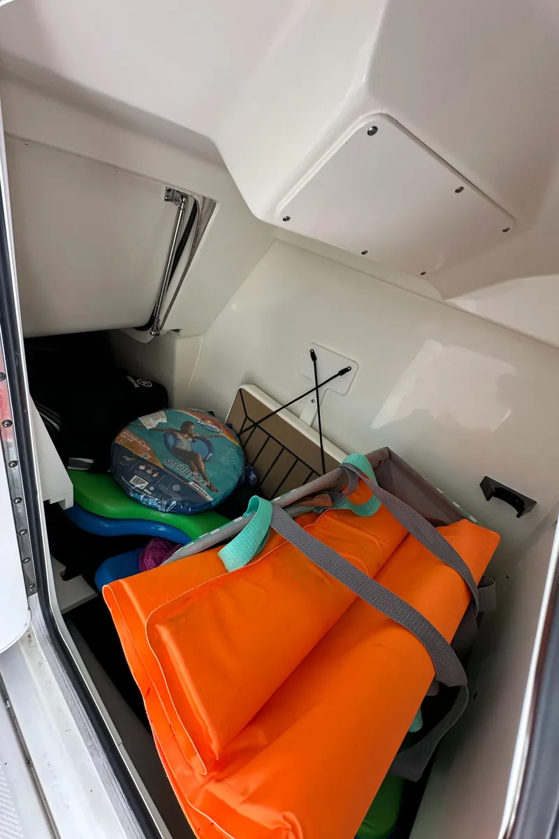 Slide: The Image of Storage compartment of 2021 Boston Whaler 240 Vantage with life jackets and beach gear. - 14