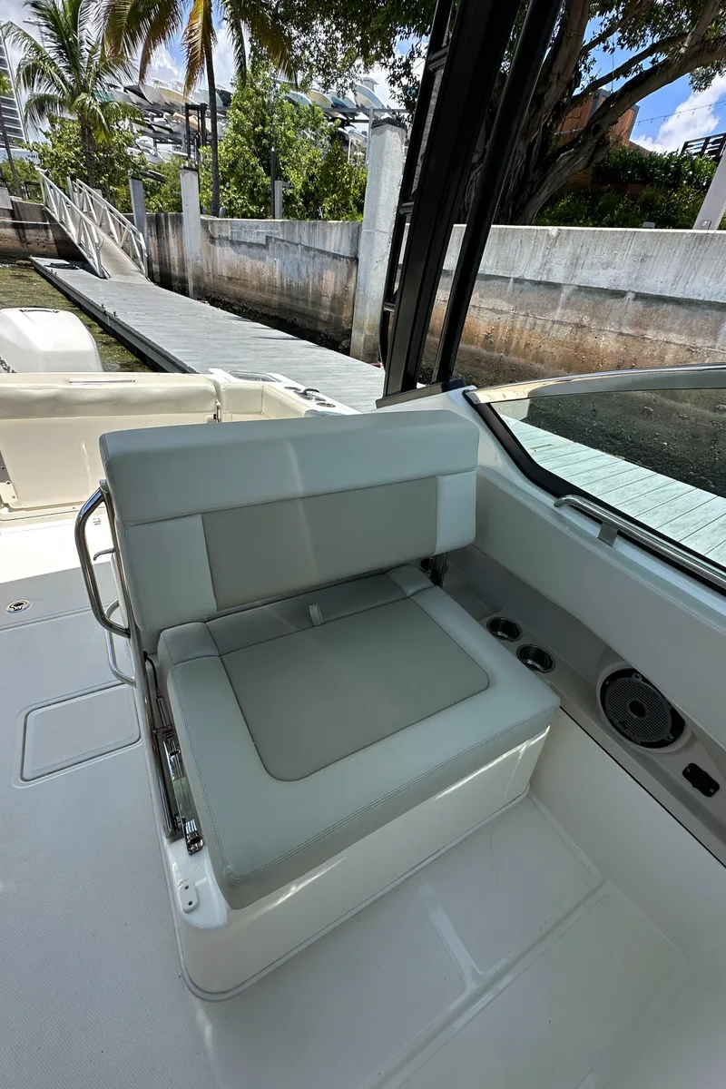 Slide: The Image of 2021 Boston Whaler 240 Vantage boat interior with cushioned seating and scenic dock view. - 16