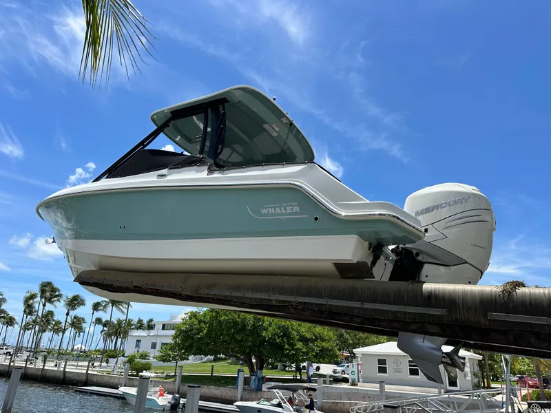 Slide: The Image of 2021 Boston Whaler 240 Vantage boat on lift, clear sky, palm trees in background. - 3