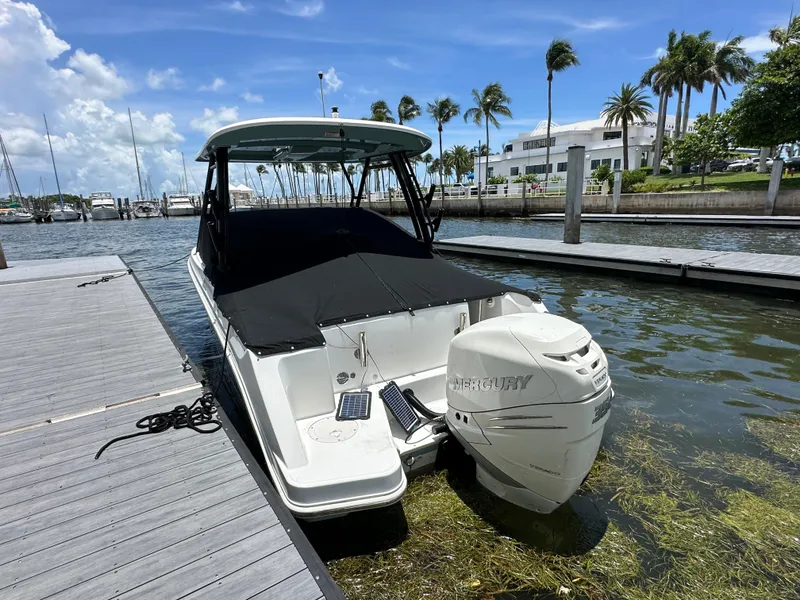 Slide: The Image of 2021 Boston Whaler 240 Vantage docked, featuring a Mercury outboard motor, under a sunny sky. - 9