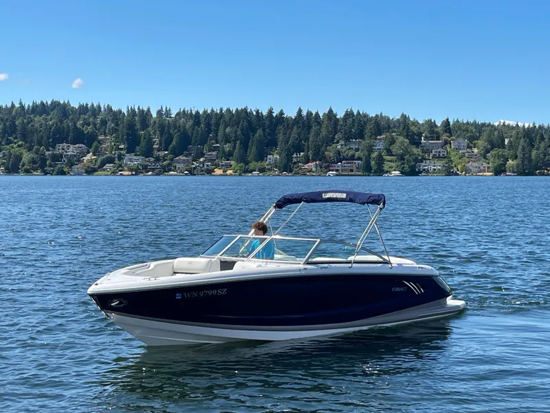 Slide: The Image of 2011 Cobalt A25 boat on a serene lake with forested shoreline. - 2