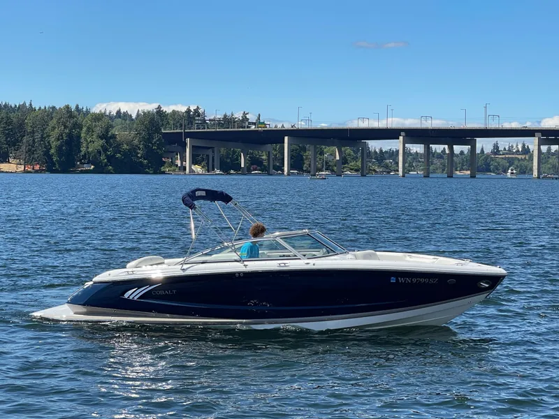 Slide: The Image of 2011 Cobalt A25 boat cruising on a scenic lake with a bridge in the background. - 5