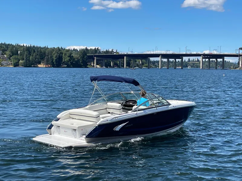 Slide: The Image of 2011 Cobalt A25 boat cruising on a sunny lake near a bridge. - 6